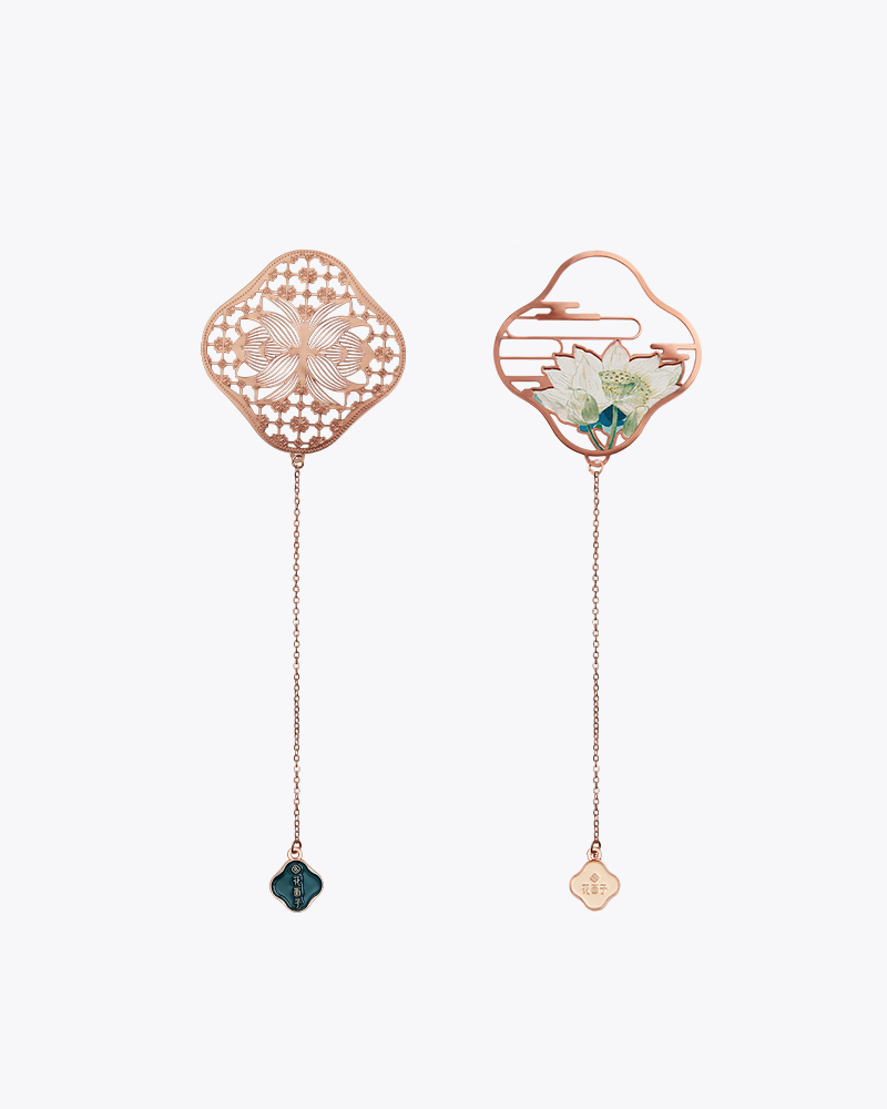Two slender bookmarks with lotus designed tops and chains with smaller lotus heads on the ends presented on a white background. They are pink, green, and white. The one on the left has an intricate design in the center; the one on the right has a lotus in the center.